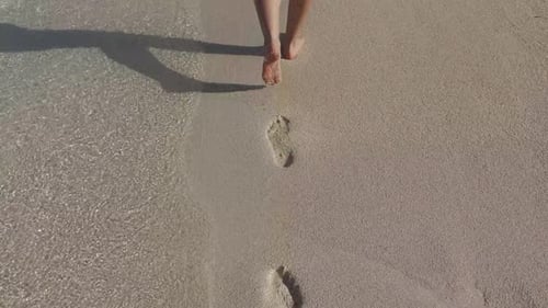 Barefoot Woman Walks Along Sandy Beach