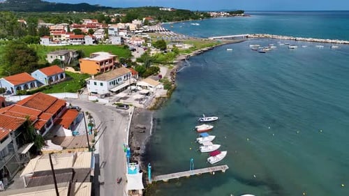 Aerial drone tracking shot of coastal road and small fishing pier in North Corfu Greece