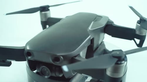 Nahaufnahme einer Drohne mit Kameraobjektiv und Propellern, silbergraue Farbe, auf einem drehbaren 360-Grad-Ständer