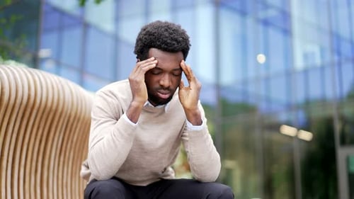 Adult Massaging Temples While Sitting Outside Office