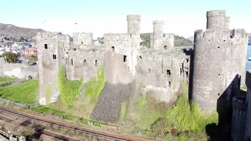 Medieval Conwy castle Welsh market town ruins aerial rising orbit left view across historical harbou