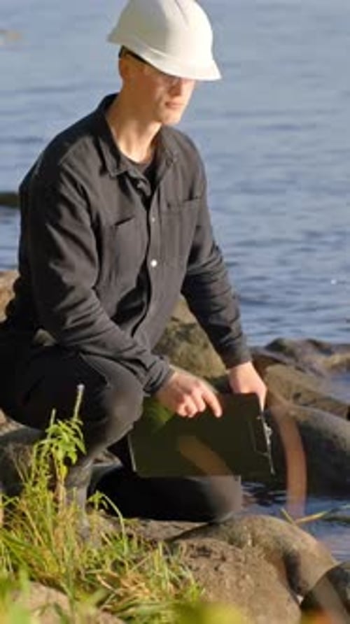 Trabajador de campo frota rocas junto al agua durante un control ambiental