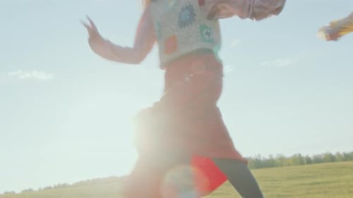 Excited Couple Running through Sunlit Field and Playing Tag Game
