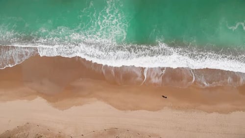Aerial view ascending top down of Beautiful beach with white sand and foaming waves crushing against