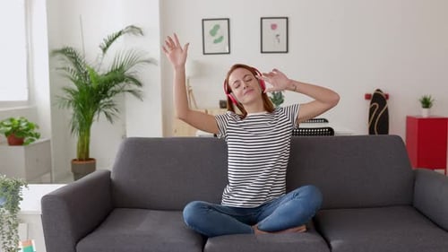 Woman Dancing to Music on Sofa at Home