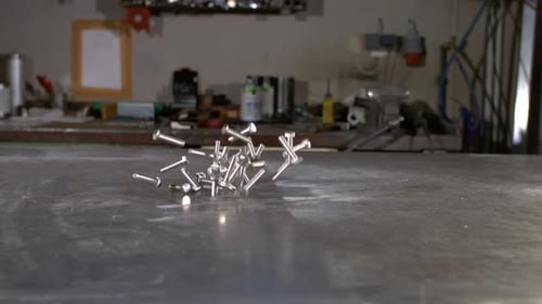 Screws falling on a metal table in a metal shop. Super slow motion in 800fps