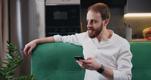 Young Man Using Phone at Home on Couch