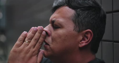 Hombre rezando con las manos en gesto de oración, cabeza inclinada hacia arriba, ojos cerrados, buscando ayuda