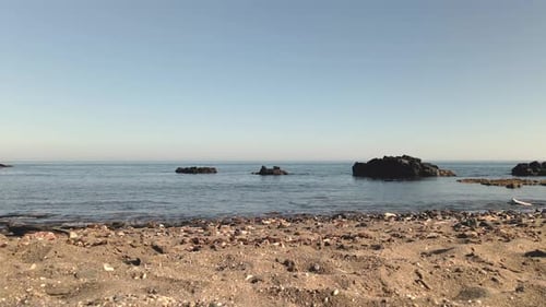 Sandy pebble beach overlooking rough rugged rocky jagged formations on coastline seascape