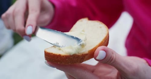 Close-up of woman spreading butter on bread. Clip. Thick piece of butter is smeared