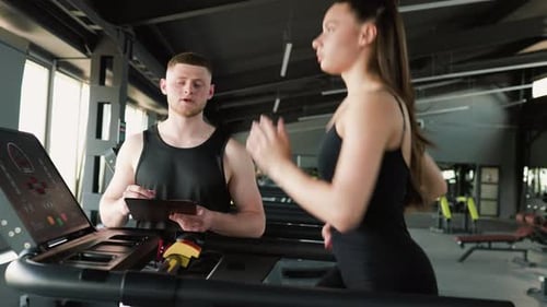 Entrenador personal masculino motivado que empuja a una corredora a alcanzar nuevas alturas