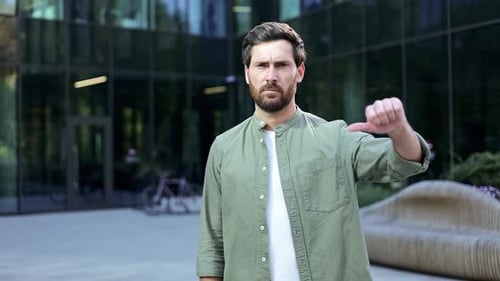 Man Gives Thumbs Down Gesture in City Setting