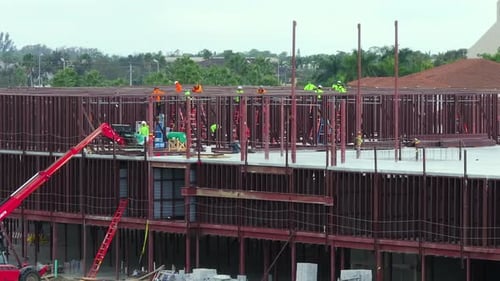 Baustelle mit Bauarbeitern, die Metallrahmenwände zusammenbauen, Luftaufnahme einer großen Bebauung