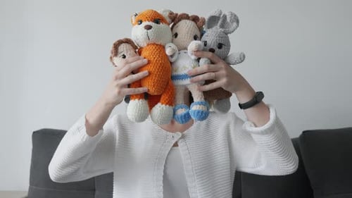 Woman Holding Stuffed Animals at Home Smiling