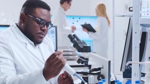 Scientist Examining Sample Under Microscope in Lab