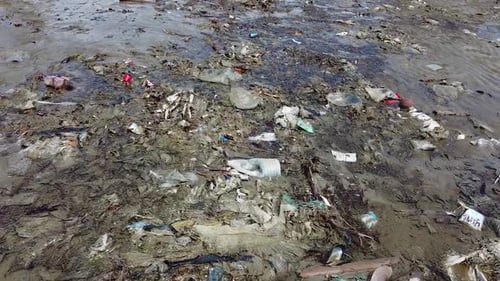 AERIAL Close Up Of Rubbish And Debris Adrift On A Beach