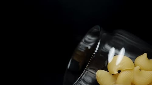 Pasta Shells Being Poured into Glass Bowl