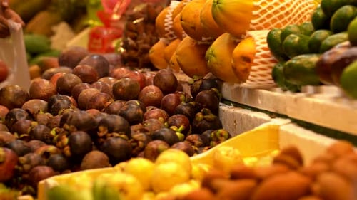 A Seller is Putting Thai Fruits Into a Bag on the Counter