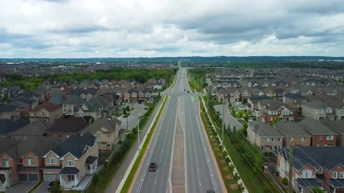 Aerial view of suburban neighbourhood flying forward over a street with houses on either side