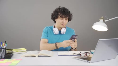 Smiling Young Adult Using Phone at Desk Indoors