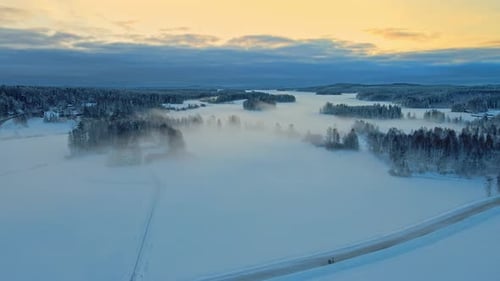 Foggy, snowy fields and forest on a beautiful winter morning sunrise