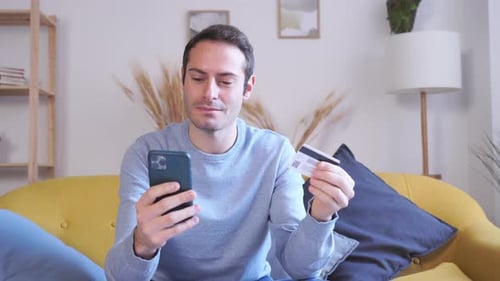 Young Adult on Couch Uses Phone and Card