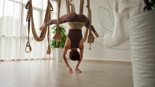 Woman Performs Aerial Yoga Handstand Indoors