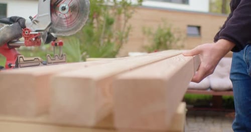 Man cutting wood with miter saw outdoors