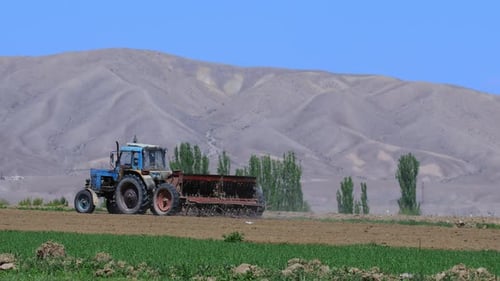 Tractor Cultivating Field in Rural Mountainous Landscape