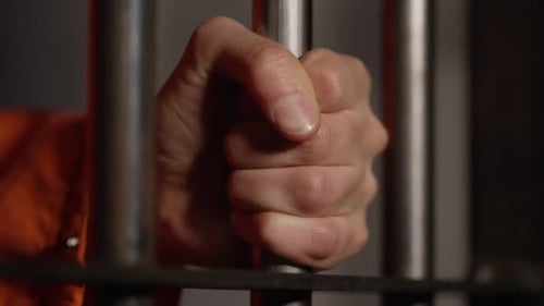 American Prison System - A man holding the cell bars