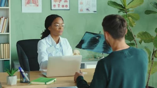 Professional Female Private Clinic Doctor Examining Xray of Lungs of Male Patient in the Hospital