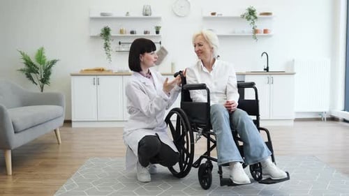 Female Doctor Talking with Senior Patient in Wheelchair