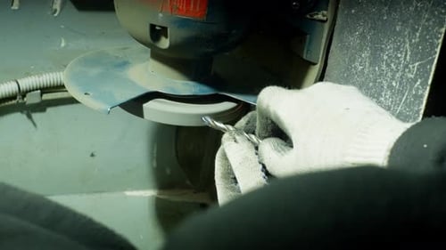A Vertical Shot of a Man Holding a Drill and Sharpening It on a Machine