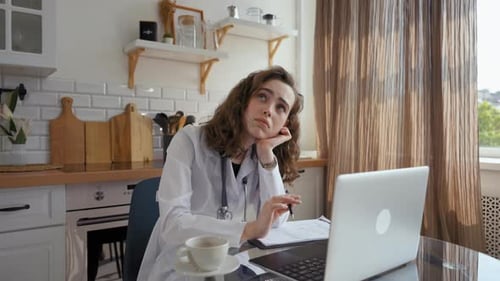 Tired Doctor Working at Home on Laptop