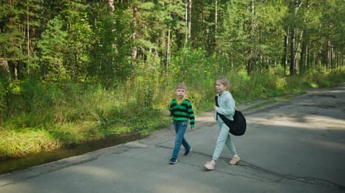 Siblings Strolling Along Tarred Road Surrounded By Forest