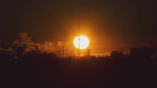 Un énorme soleil se lève derrière les toits de la ville