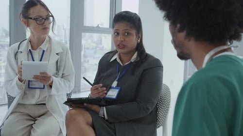 Female Manager Talking to Doctors during Meeting in Clinic