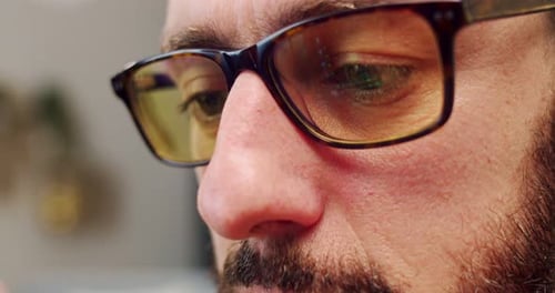 Close Up of Caucasian Young Man in Glasses and with Beard Looking at Screen of Gadget While Using It