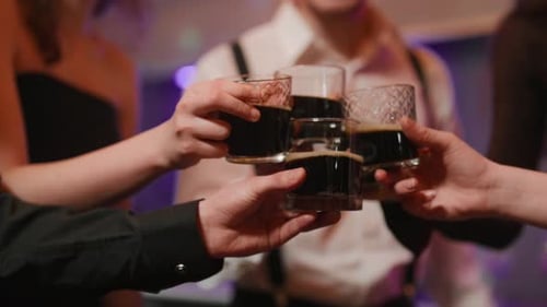 Friends Toasting Dark Liquor at Nighttime Celebration