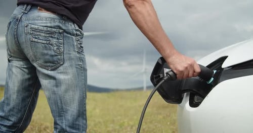 Close Up Progressive Man with His Electric Car EV Car Recharging Energy From Charging Station on