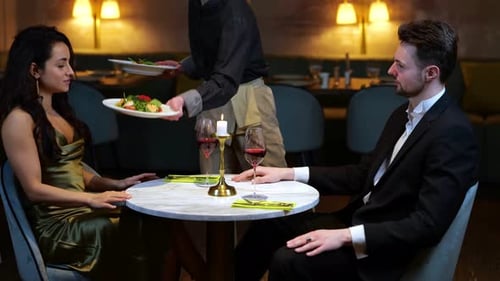 Waitress Bringing Salads for Young Couple Having Romantic Date in the Restaurant Lifestyle Love