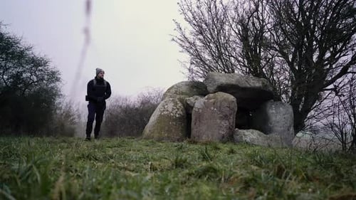 Person walking up and touching an old stone dolmen megalithic monument site