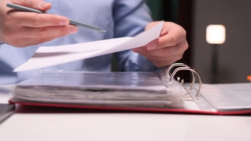 Office Worker Checking Documents with Pen and Folder at Night