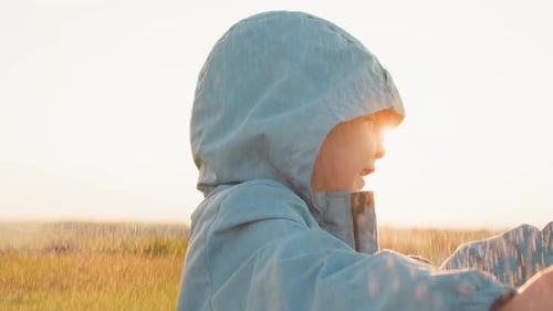 Smiling Child Playing in Golden Rain Shower Outdoors