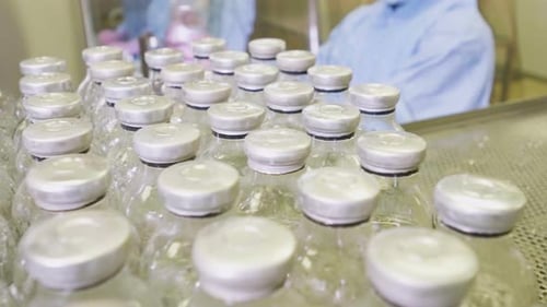 Un spécialiste en gros plan en uniforme de protection bleu met des bouteilles en verre avec un produit chimique
