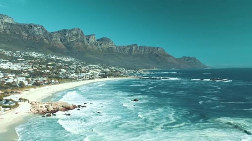 Aerial drone view of distant cityscape amidst arid mountains and beach