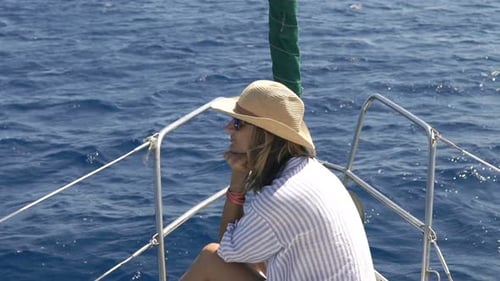Pensive woman sailing a yacht on a blue sea in super slow motion on a summer holiday