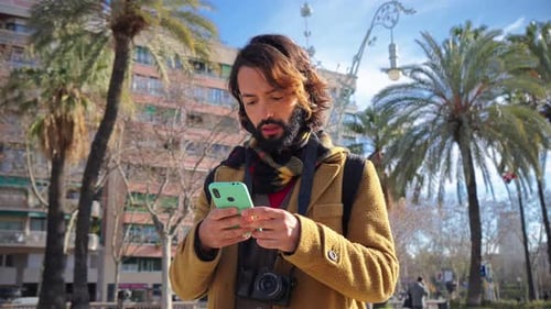 Happy Bearded Man Using a Cellphone App for Browsing on Internet
