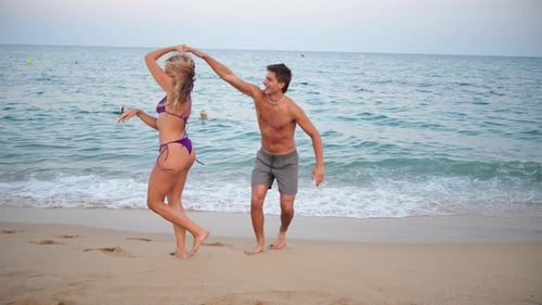 Joyful Couple Dancing By the Shoreline During a Sunny Summer Day at the Beach Creating Happy