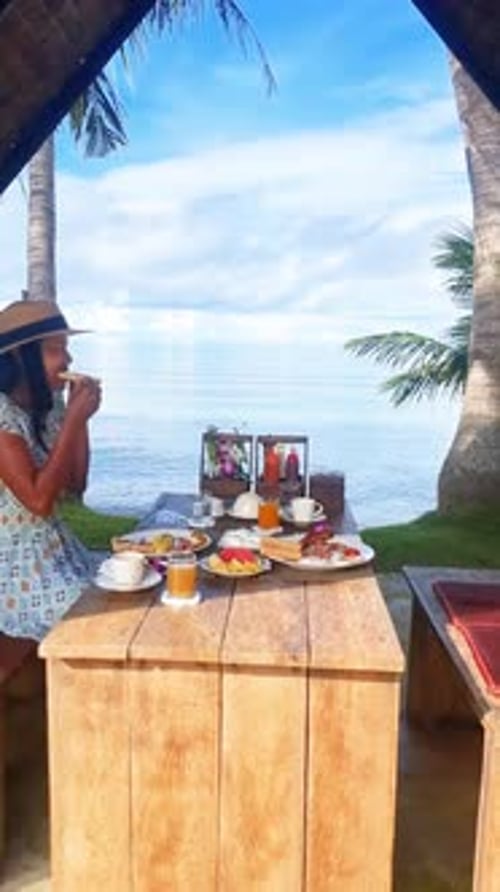 a Woman is Sitting at a Table with a View of the Ocean at Breakfast Koh Mak Thailand